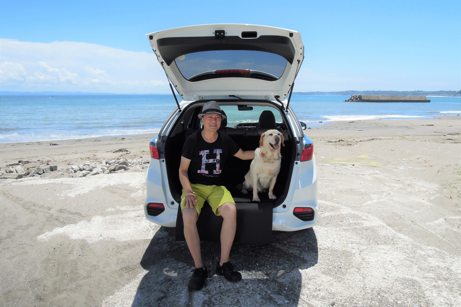 砂浜に駐車したクルマと筆者の青山尚暉さん
